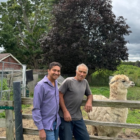 Guru Bhat visiting a local farm and meeting a farmer with alpaca