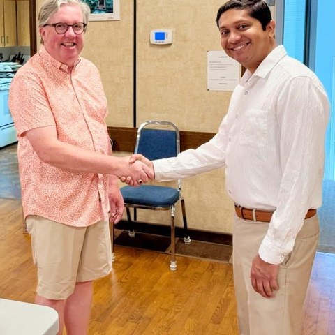 Guru Bhat shaking hands with community member at town hall